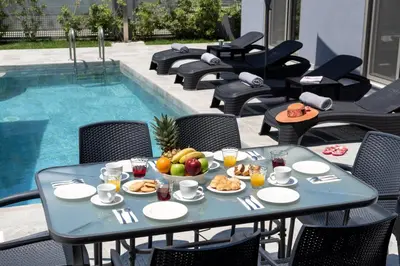 a table with food on it next to a swimming pool at Villa Ampela by PosarelliVillas in Agia Marina Nea Kydonias
