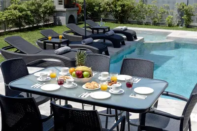 a table with a bowl of fruit next to a pool at Villa Ampela by PosarelliVillas in Agia Marina Nea Kydonias