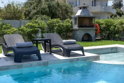two chairs and a table next to a swimming pool at Villa Ampela by PosarelliVillas in Agia Marina Nea Kydonias