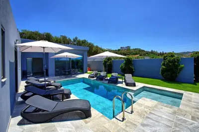 a swimming pool with lounge chairs and umbrellas at Villa Zaneti by PosarelliVillas in Agia Marina Nea Kydonias