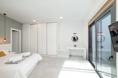 a white room with two beds and a bathroom at Villa Zaneti by PosarelliVillas in Agia Marina Nea Kydonias