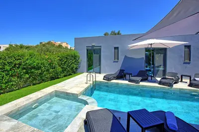 a swimming pool with chairs and an umbrella at Villa Zaneti by PosarelliVillas in Agia Marina Nea Kydonias