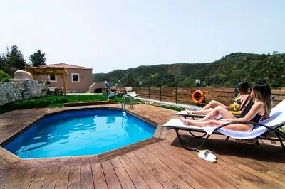 two women sitting in chairs next to a swimming pool at Ampelos Cretan Villa - Private Pool & Heated Ozone Jacuzzi in Gerolakkos