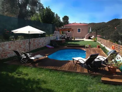 a pool with chairs and an umbrella in a yard at Ampelos Cretan Villa - Private Pool & Heated Ozone Jacuzzi in Gerolakkos