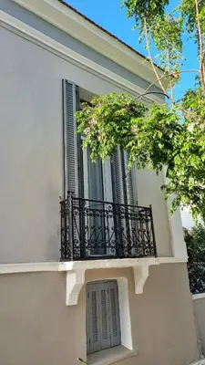 a white building with a balcony and trees at Philoxenia Residence Chania City Centre in Chania Town