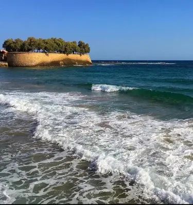 a beach with waves and trees in the ocean at Philoxenia Residence Chania City Centre in Chania Town