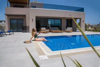 a woman sitting on the edge of a swimming pool at Imperium Luxury Villas-Sauna, Jacuzzi, Heated Pool & Gym-Chania in Kato Galatas