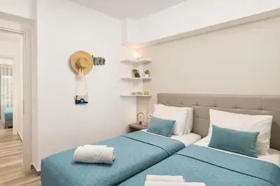 two beds in a bedroom with blue and white at Aquadia Beach Apartment in Chania Town
