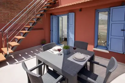 a table and chairs on a balcony with a staircase at Mouse House with Sea View and Mini Pool in Plataniás