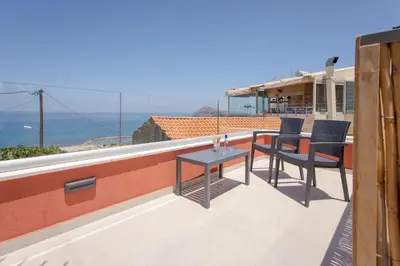 a patio with two chairs and a table on a roof at Mouse House with Sea View and Mini Pool in Plataniás