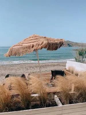a straw umbrella on a beach with the ocean at Esperanto seafront studio in Agia Marina Nea Kydonias