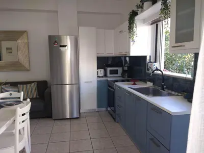 a kitchen with blue cabinets and a stainless steel refrigerator at Cozy Home (close to the beach) in Agia Marina Nea Kydonias