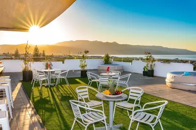 a rooftop patio with tables and chairs and a tub at Louladakis Apartments in Kolymvari