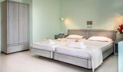 a bedroom with two beds with white sheets and towels at Louladakis Apartments in Kolymvari