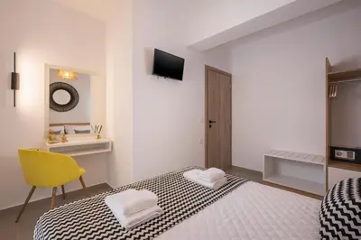 a bedroom with a bed and a yellow chair at INDIGO BLUE Seaside Deluxe Apartments in Kissamos