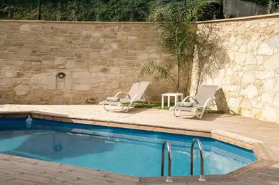 two lounge chairs and a swimming pool next to a wall at Villa Vanka in Chania Town