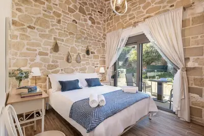 a bedroom with a bed and a stone wall at Villa Vanka in Chania Town