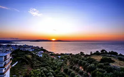 a sunset over the water with a city at Dreamy View Inn in Chania Town