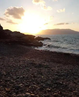 a sunset on a rocky beach with the ocean at jAne's house in Ravdhoúkha