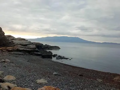 a beach with rocks and the ocean on a cloudy day at jAne's house in Ravdhoúkha