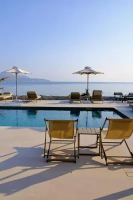 a pool with chairs and umbrellas next to the ocean at Kera Studios in Kalyves