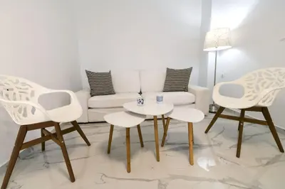 a living room with two white chairs and a white couch at Aria apts 100 m from the beach by PosarelliVillas in Kolymvari