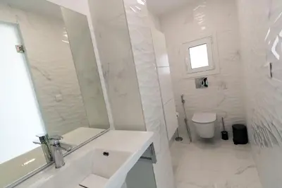 a white bathroom with a sink and a toilet at Aria apts 100 m from the beach by PosarelliVillas in Kolymvari