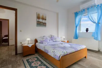 a bedroom with a bed with blue curtains and a window at Villa Albion in Kolymvari
