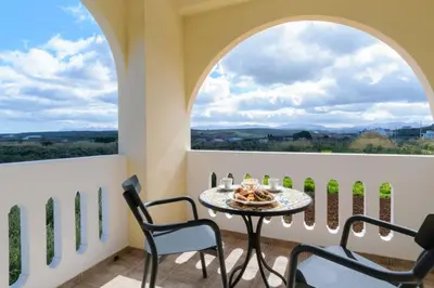 a balcony with a table and chairs and two windows at Villa Albion in Kolymvari