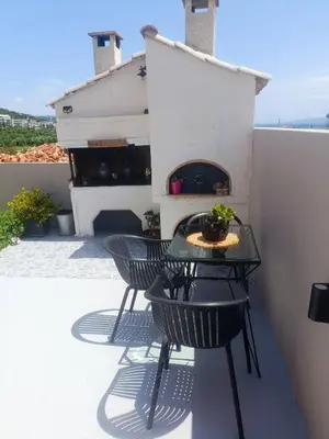a patio with two chairs and a table with a fireplace at Sunrise Apartment 2 in Souda