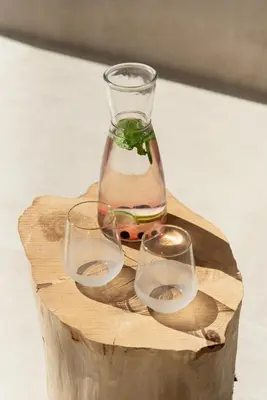 two wine glasses and a vase on a wooden block at Esperanto Seafront suites in Agia Marina Nea Kydonias