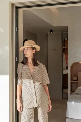 a woman wearing a hat and a striped jumpsuit at Esperanto Seafront suites in Agia Marina Nea Kydonias