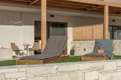 two beds sitting on the grass outside of a house at Esperanto Seafront suites in Agia Marina Nea Kydonias