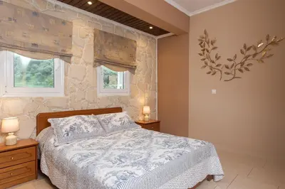 a bedroom with a bed and a stone wall at Villa Kalaitsidi - plunge pool, gym and unique gardens in Skinés