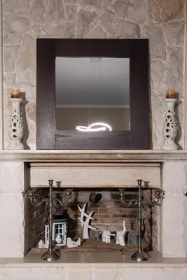 a fireplace with a mirror on top of it at Villa Kalaitsidi - plunge pool, gym and unique gardens in Skinés