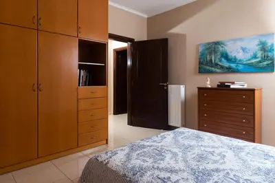 a bedroom with a bed and wooden cabinets and a dresser at Villa Kalaitsidi - plunge pool, gym and unique gardens in Skinés