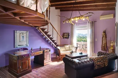 a living room with purple walls and a wooden staircase at Villa Milon by PosarelliVillas in Skinés