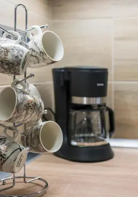 a rack of coffee mugs in front of a coffee maker at Cataleya Villa Chania in Daratso