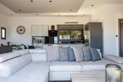 a living room with a white couch and a kitchen at ÉTHAFOS Luxury Apartment in Tsikalariá