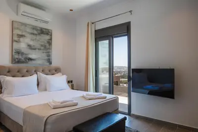 a bedroom with a bed with a tv and a window at ÉTHAFOS Luxury Apartment in Tsikalariá