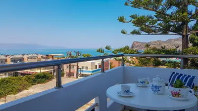 a white balcony with a table and a view of the ocean at Giannis & Maria Gramvousaki Apts in Agia Marina Nea Kydonias