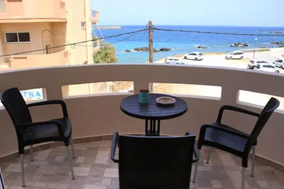 a table and chairs on a balcony with a view of the ocean at THALIA APARTMENTS CHANlA in Chania Town