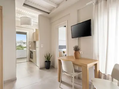 a dining room with a table and a tv on a wall at Anthos in Frangokastello