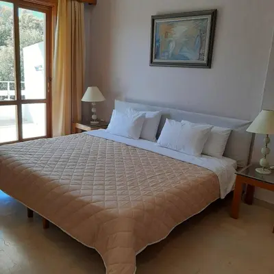 a large bed in a hotel room with two lamps at Hotel Elman in Palaiochóra