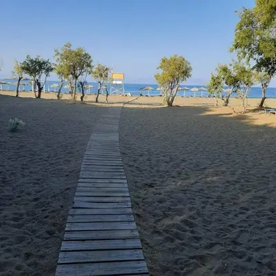 a wooden path on a beach with trees in the background at Hotel Elman in Palaiochóra