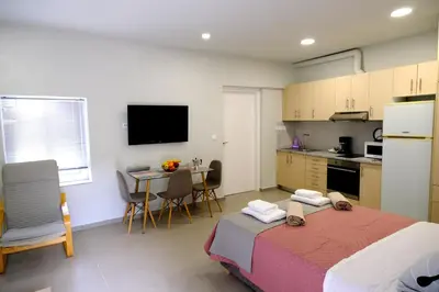 a bedroom with a bed and a kitchen with a table at Erinaki Apartments in Kissamos