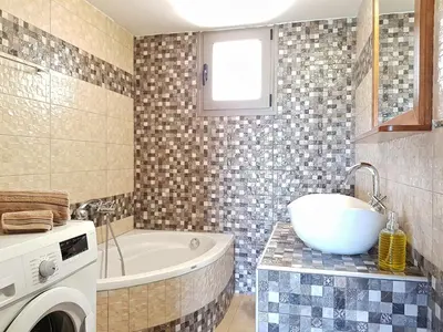 a bathroom with a tub and a sink and a washing machine at New Villa Kalimera, view to Falasarna beach in Plátanos