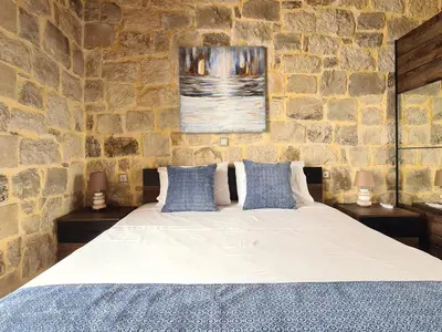a bedroom with a large bed in a stone wall at New Villa Kalimera, view to Falasarna beach in Plátanos