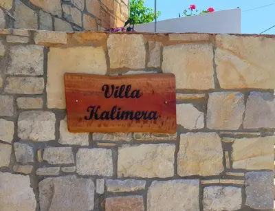 a sign on the side of a stone wall at New Villa Kalimera, view to Falasarna beach in Plátanos