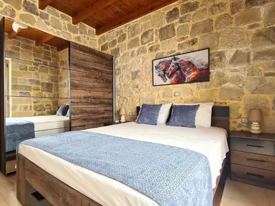 a bedroom with a bed and a stone wall at New Villa Kalimera, view to Falasarna beach in Plátanos